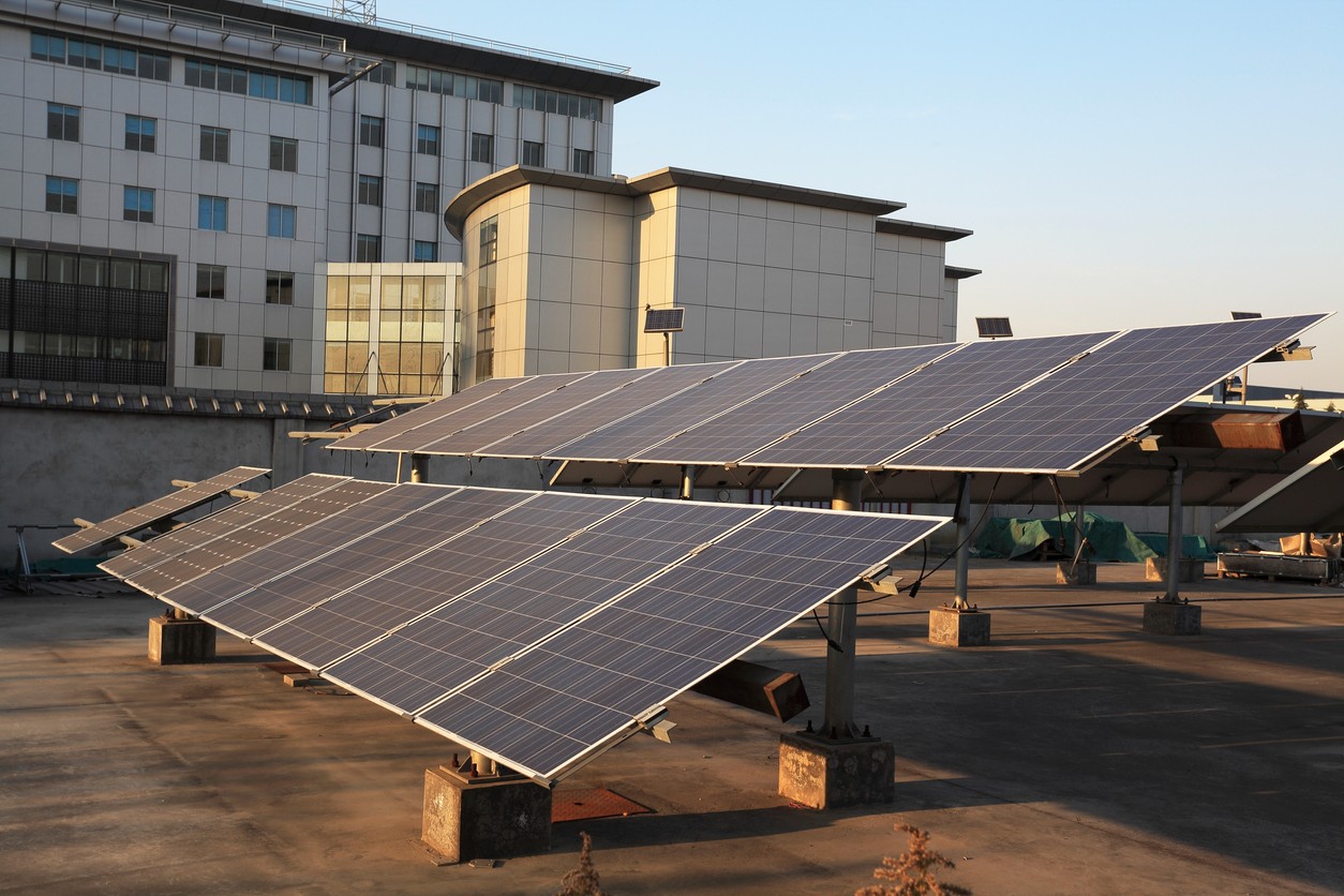 Commercial rooftop solar panel array installed beside a large building.